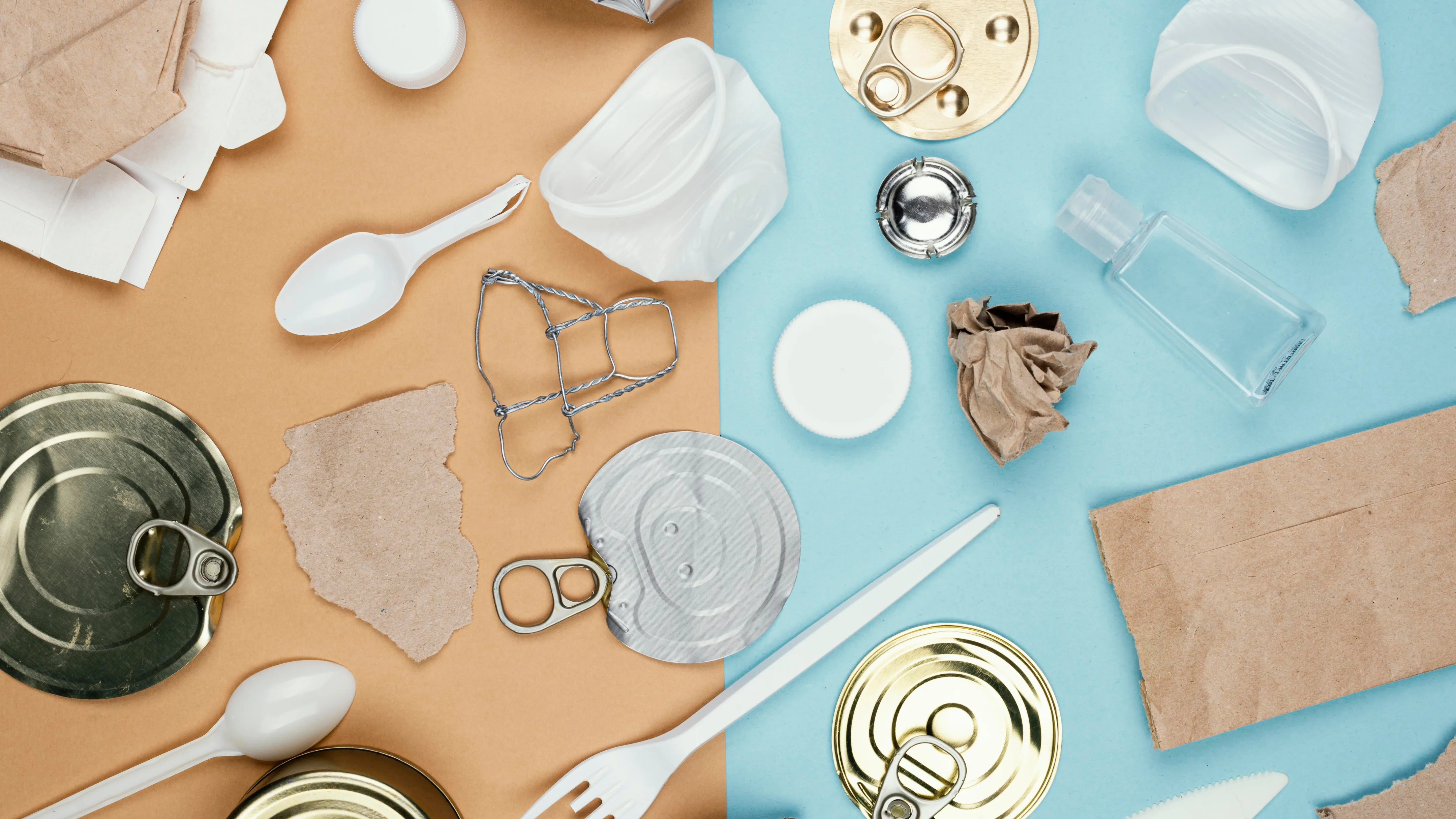 Mixed waste on a background split into two colors, brown and blue, representing the separation of recyclable materials such as plastic, paper, and metal.